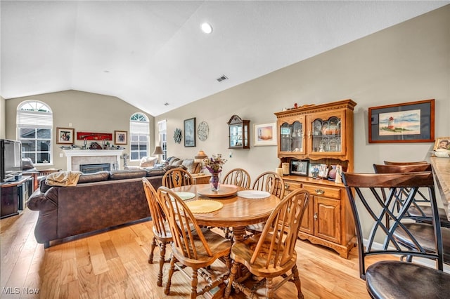 3845 Windsor Bridge Cir, Huron, OH 44839 - dining space featuring lofted ceiling, light wood-style floors, and a fireplace