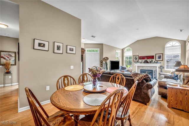 3845 Windsor Bridge Cir, Huron, OH 44839 - dining area featuring light wood finished floors, lofted ceiling, and a glass covered fireplace