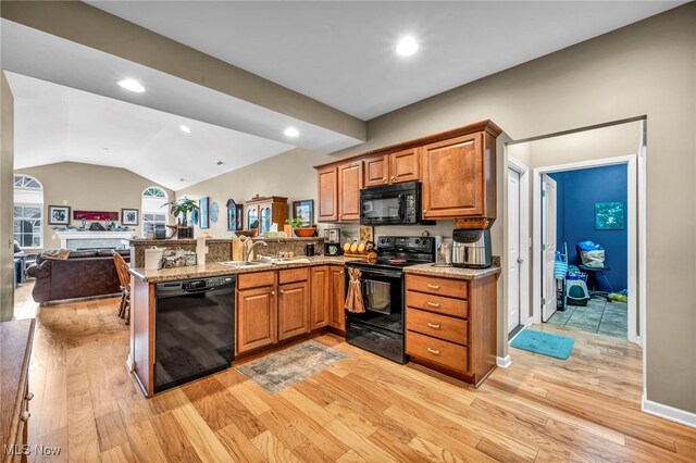 3845 Windsor Bridge Cir, Huron, OH 44839 - kitchen featuring black appliances, a peninsula, brown cabinetry, light wood-style flooring, and vaulted ceiling