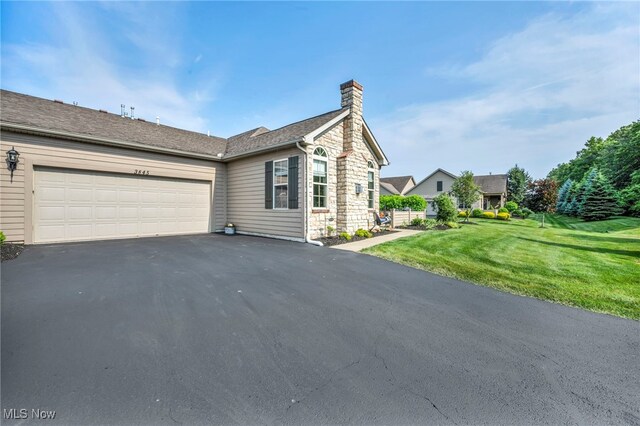 3845 Windsor Bridge Cir, Huron, OH 44839 - view of front facade with a chimney, asphalt driveway, a front yard, an attached garage, and stone siding