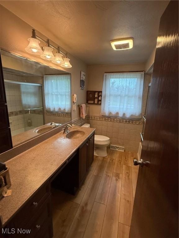 213 Highland Park, Bloomingdale, OH 43910 - bathroom with wood finished floors, a shower with door, vanity, tile walls, and a textured ceiling