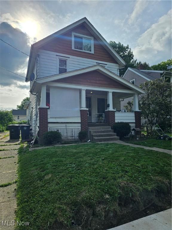 1258 Wilbur Ave, Akron, OH 44301 - view of front of house with brick siding, a front yard, and covered porch