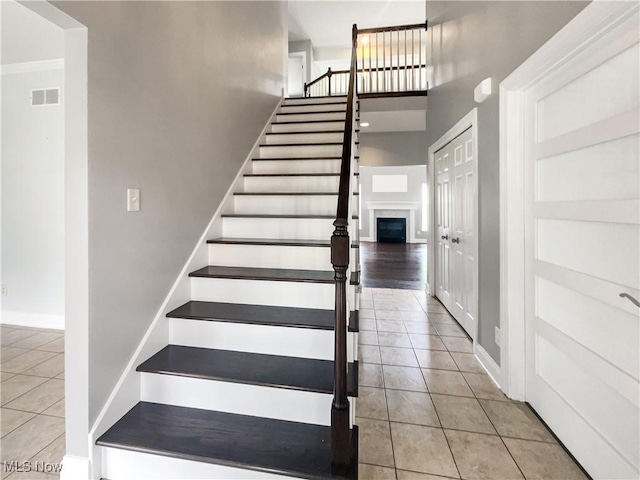 3217 Deborah Ct, Uniontown, OH 44685 - staircase featuring tile patterned flooring, a fireplace, and a high ceiling