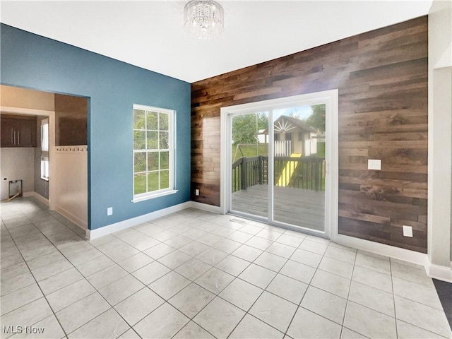 3217 Deborah Ct, Uniontown, OH 44685 - empty room featuring wood walls, plenty of natural light, an accent wall, a chandelier, and light tile patterned floors
