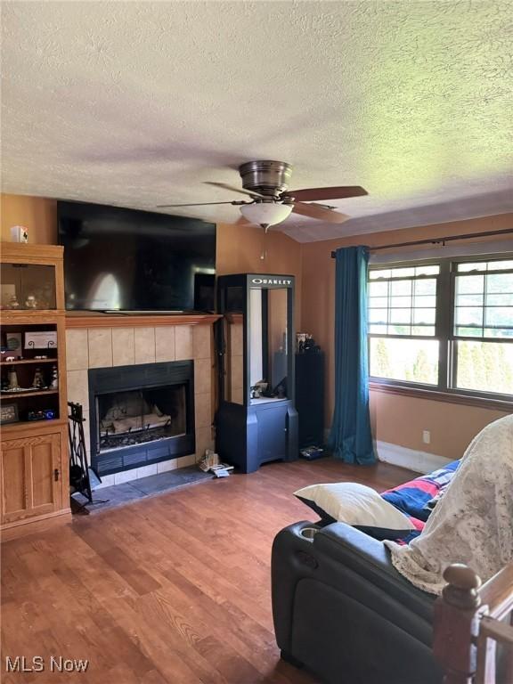 20684 Albion Rd, Strongsville, OH 44149 - living area with a textured ceiling, wood finished floors, a tile fireplace, and ceiling fan