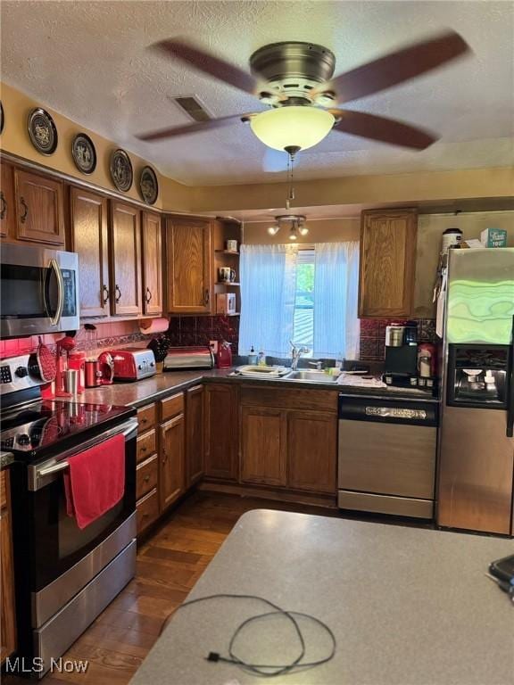 20684 Albion Rd, Strongsville, OH 44149 - kitchen with appliances with stainless steel finishes, brown cabinetry, tasteful backsplash, ceiling fan, and dark wood-type flooring