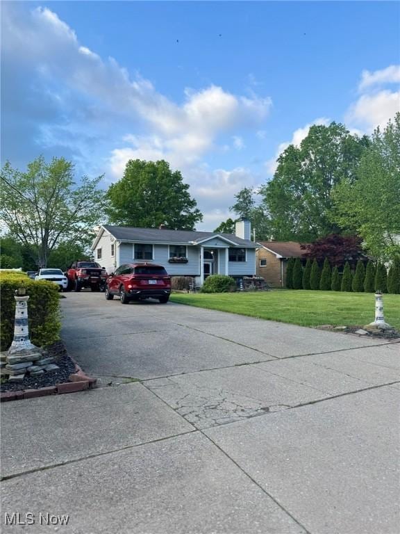 20684 Albion Rd, Strongsville, OH 44149 - view of front of house featuring concrete driveway, a front lawn, and a chimney