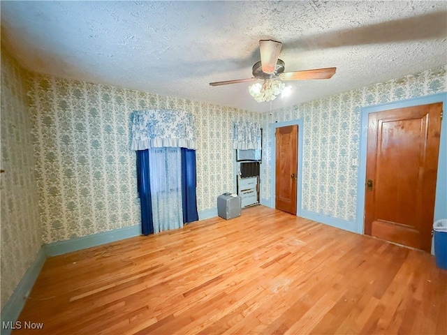 2323 Scholl Rd, University Heights, OH 44118 - unfurnished room with wood finished floors, a ceiling fan, wallpapered walls, and a textured ceiling