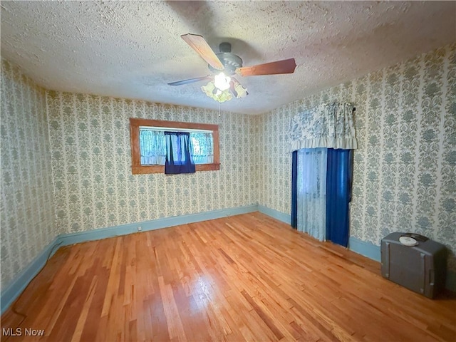 2323 Scholl Rd, University Heights, OH 44118 - empty room with hardwood / wood-style floors, a textured ceiling, ceiling fan, and wallpapered walls