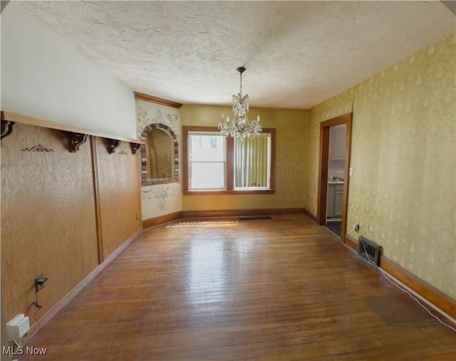 2323 Scholl Rd, University Heights, OH 44118 - unfurnished dining area featuring a chandelier, wood-type flooring, and a textured ceiling