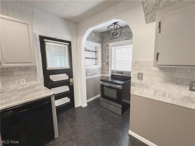 2323 Scholl Rd, University Heights, OH 44118 - kitchen with electric range, arched walkways, tasteful backsplash, light countertops, and a textured ceiling