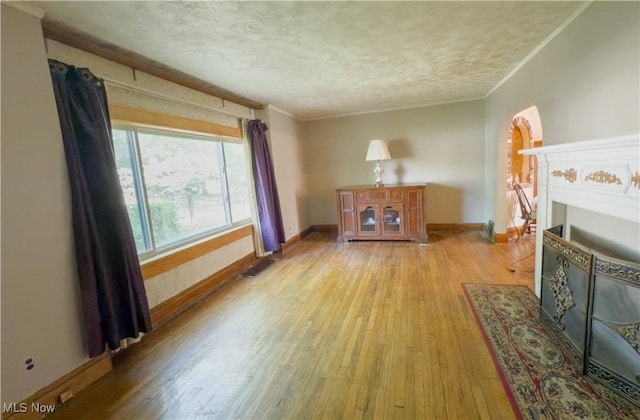 2323 Scholl Rd, University Heights, OH 44118 - living room featuring light wood-type flooring, a textured ceiling, ornamental molding, and a fireplace