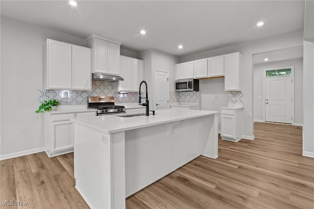 1809 Muirfield Ln, Painesville, OH 44077 - kitchen with appliances with stainless steel finishes, an island with sink, white cabinets, decorative backsplash, and recessed lighting