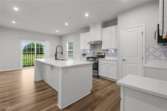 1809 Muirfield Ln, Painesville, OH 44077 - kitchen with stainless steel gas range, under cabinet range hood, backsplash, white cabinets, and an island with sink