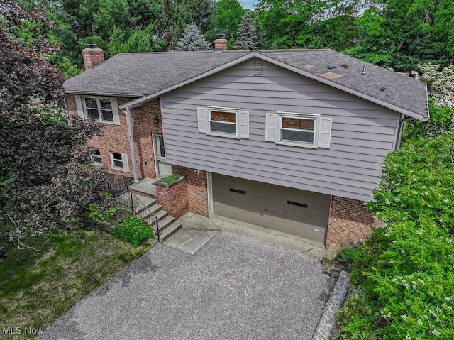 4671 Milford Dr, Perry, OH 44081 - view of front of home with a chimney, a garage, brick siding, and roof with shingles