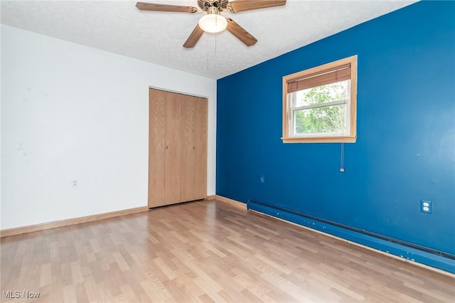 4671 Milford Dr, Perry, OH 44081 - unfurnished bedroom featuring a baseboard heating unit, wood finished floors, a closet, a ceiling fan, and a textured ceiling