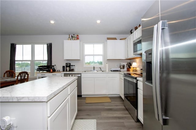 393 Slate Rdg, Barberton, OH 44203 - kitchen featuring stainless steel appliances, light countertops, white cabinets, a kitchen island, and wood finished floors
