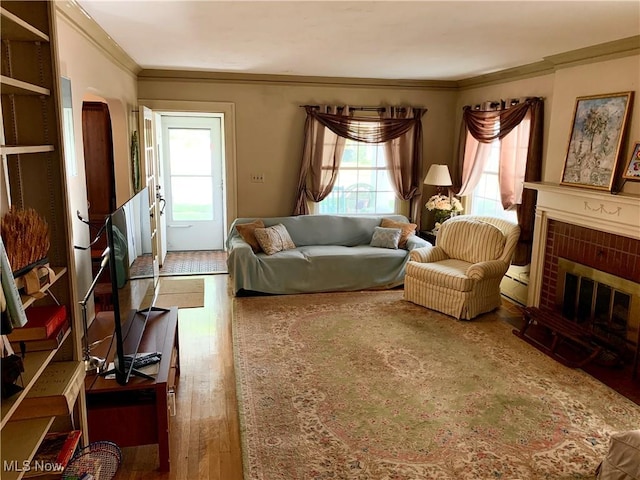 21437 Hillsdale Ave, Fairview Park, OH 44126 - living room with ornamental molding, plenty of natural light, wood finished floors, a brick fireplace, and a baseboard radiator