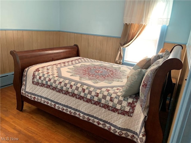 21437 Hillsdale Ave, Fairview Park, OH 44126 - bedroom featuring a baseboard heating unit, wood finished floors, a wainscoted wall, and wooden walls