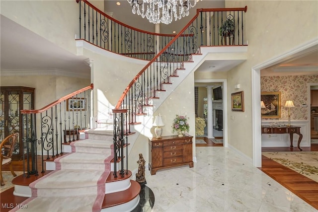 23225 Wingedfoot Dr, Westlake, OH 44145 - stairs with crown molding, a high ceiling, marble tiled floors, and a chandelier