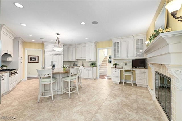 23225 Wingedfoot Dr, Westlake, OH 44145 - kitchen featuring white cabinets, a breakfast bar, a center island with sink, recessed lighting, and glass insert cabinets