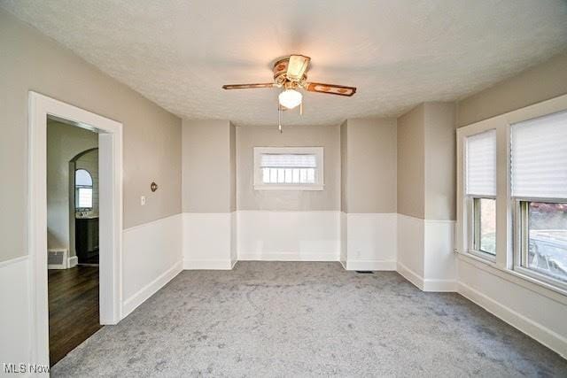 608 Columbus Ave NW, Canton, OH 44708 - unfurnished room with a ceiling fan, carpet floors, a textured ceiling, and a wainscoted wall