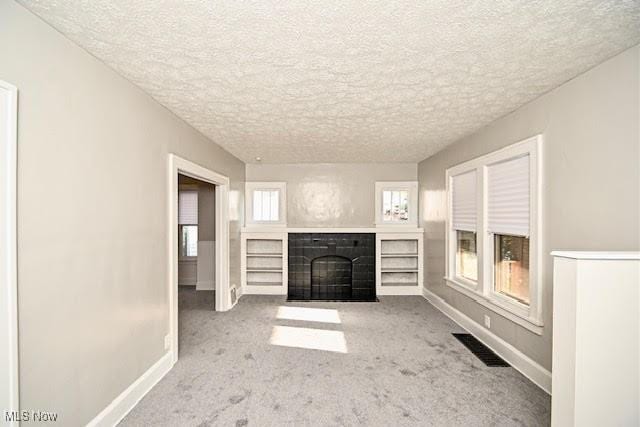 608 Columbus Ave NW, Canton, OH 44708 - unfurnished living room featuring a tile fireplace, carpet floors, and a textured ceiling
