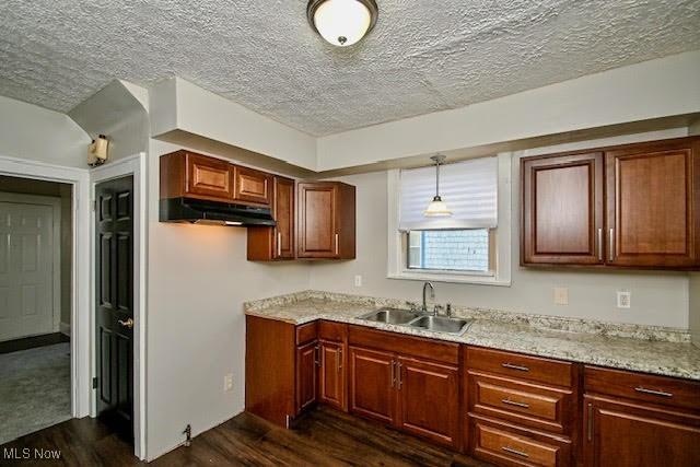 608 Columbus Ave NW, Canton, OH 44708 - kitchen featuring dark wood-type flooring, a textured ceiling, light stone countertops, hanging light fixtures, and under cabinet range hood