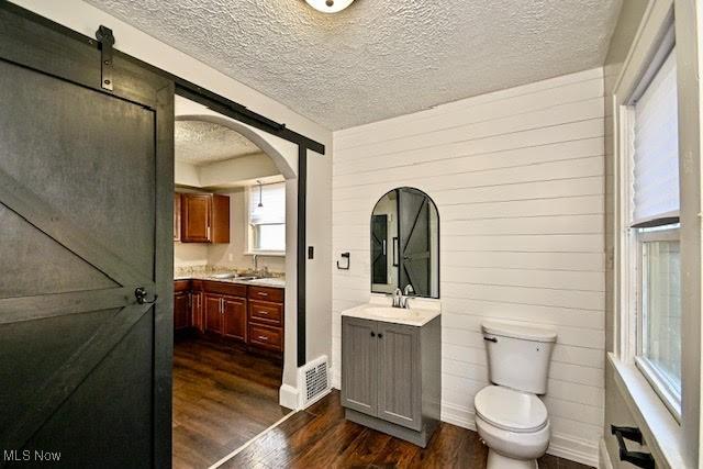 608 Columbus Ave NW, Canton, OH 44708 - bathroom featuring wood finished floors, vanity, a textured ceiling, and wooden walls