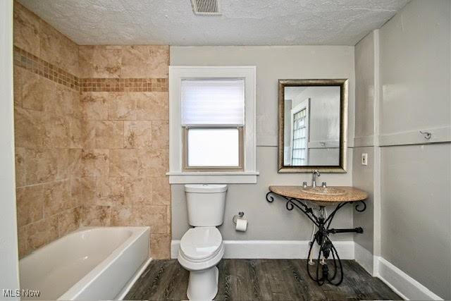 608 Columbus Ave NW, Canton, OH 44708 - full bathroom with wood finished floors, a textured ceiling, and tub / shower combination