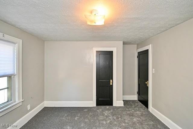 608 Columbus Ave NW, Canton, OH 44708 - unfurnished bedroom with a textured ceiling and carpet floors
