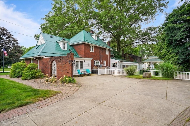 3571 Greenwich Rd, Barberton, OH 44203 - view of home's exterior featuring brick siding, a chimney, a metal roof, and concrete driveway