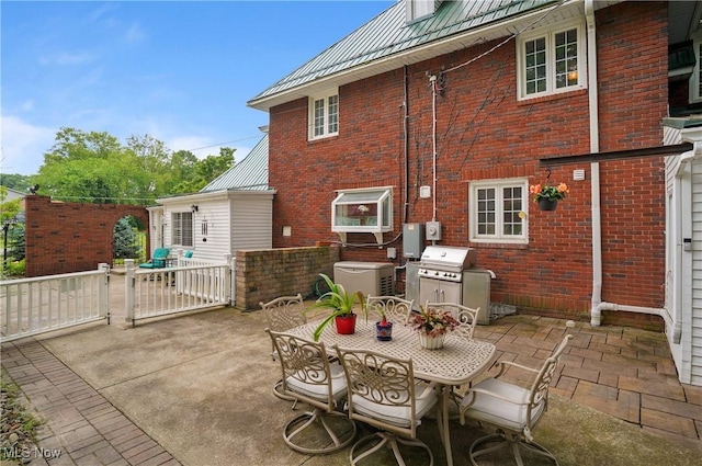 3571 Greenwich Rd, Barberton, OH 44203 - rear view of property with brick siding, a patio, outdoor dining space, and a metal roof