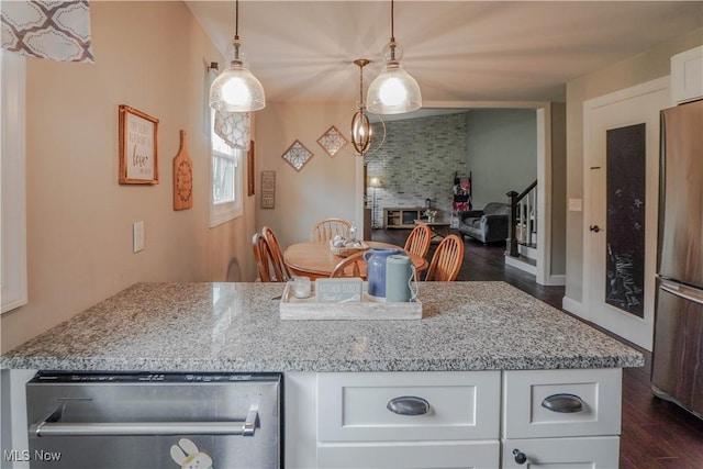 1324 Woodrow St NW, North Canton, OH 44720 - kitchen featuring appliances with stainless steel finishes, dark wood-style flooring, white cabinets, light stone counters, and decorative light fixtures