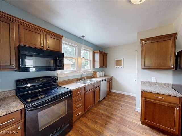 4982 14th St SW, Canton, OH 44710 - kitchen featuring black appliances, wood finished floors, brown cabinetry, and pendant lighting
