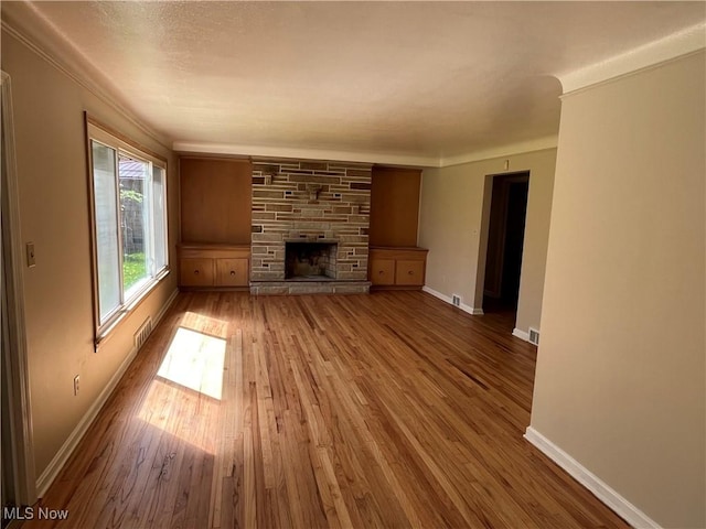 2017 Natona Rd, Euclid, OH 44117 - unfurnished living room with wood finished floors, a stone fireplace, and crown molding