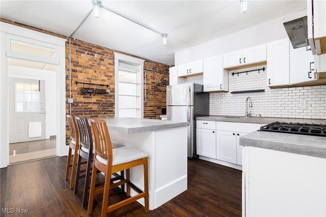 719 N 3rd St, Toronto, OH 43964 - kitchen featuring freestanding refrigerator, dark wood-type flooring, decorative backsplash, a kitchen breakfast bar, and white cabinetry