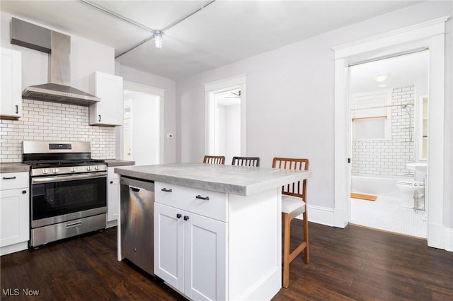 719 N 3rd St, Toronto, OH 43964 - kitchen with appliances with stainless steel finishes, wall chimney range hood, a breakfast bar area, dark wood-style flooring, and white cabinetry
