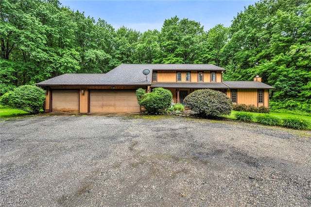 12938 Carter Rd, Leroy, OH 44077 - view of front of home featuring a garage, a chimney, driveway, and a wooded view