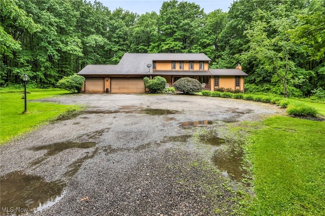 12938 Carter Rd, Leroy, OH 44077 - view of front of house with a garage, asphalt driveway, a front lawn, and a wooded view