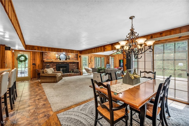 12938 Carter Rd, Leroy, OH 44077 - dining area featuring wood walls, healthy amount of natural light, a chandelier, a textured ceiling, and a fireplace