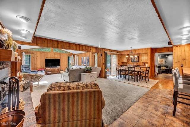 12938 Carter Rd, Leroy, OH 44077 - living area with wood walls, a chandelier, a fireplace, a textured ceiling, and tile patterned flooring
