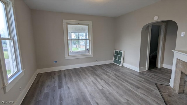 1111 2nd St NW, Canton, OH 44703 - unfurnished room with wood finished floors, a fireplace, arched walkways, and a smoke detector