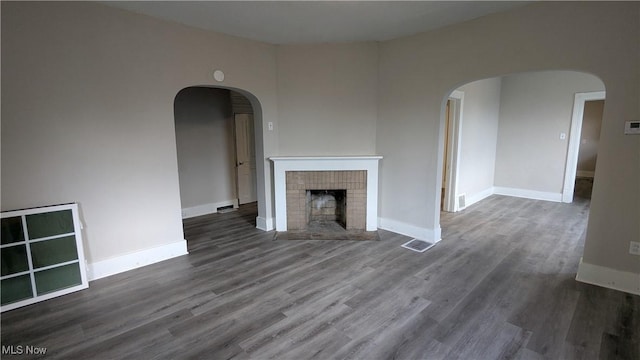 1111 2nd St NW, Canton, OH 44703 - unfurnished living room with wood finished floors, a fireplace, and arched walkways