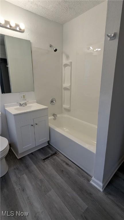 1111 2nd St NW, Canton, OH 44703 - bathroom with a textured ceiling, wood finished floors, vanity, and washtub / shower combination