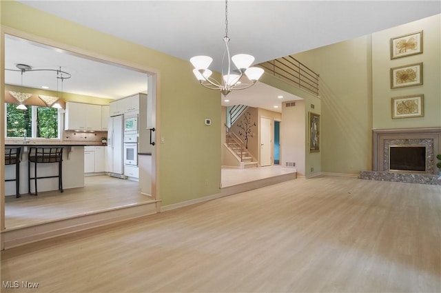 80 Hawthorne Ave, Rittman, OH 44270 - unfurnished living room with light wood-type flooring, stairs, a chandelier, and a premium fireplace