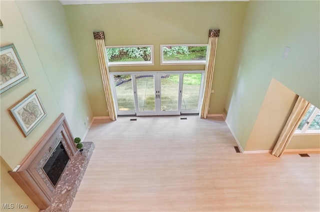 80 Hawthorne Ave, Rittman, OH 44270 - unfurnished living room with french doors, a towering ceiling, light wood finished floors, and a glass covered fireplace