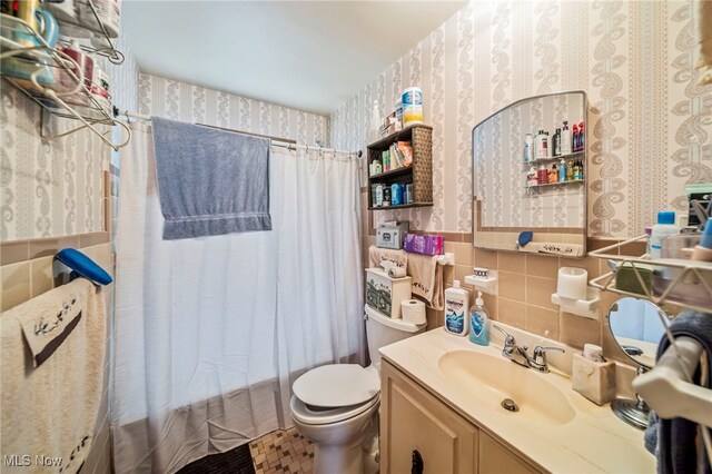 24270 Glenforest Rd, Euclid, OH 44123 - full bathroom with wallpapered walls, tile walls, vanity, and a wainscoted wall