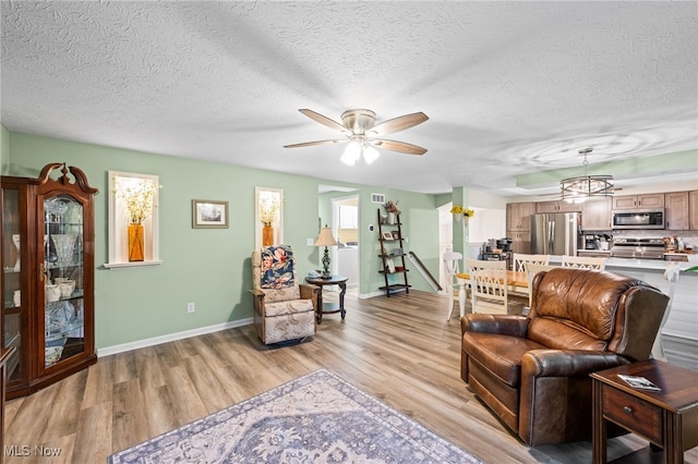 7152 Rippling Brook Ln, Concord, OH 44060 - living area with light wood-style flooring, ceiling fan, a textured ceiling, and a chandelier