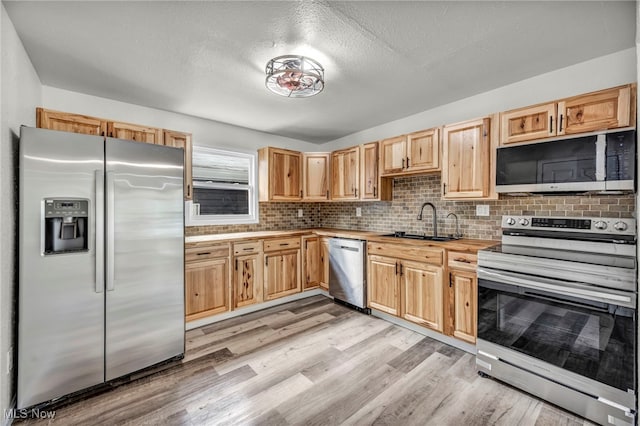 397 Furnace Rd, Conneaut, OH 44030 - kitchen featuring stainless steel appliances, light wood finished floors, decorative backsplash, and a textured ceiling
